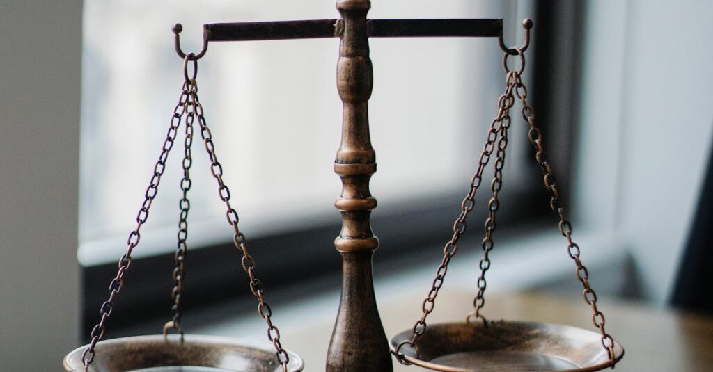 Decorative judgement scale and gavel placed on desk in light lawyer office against window